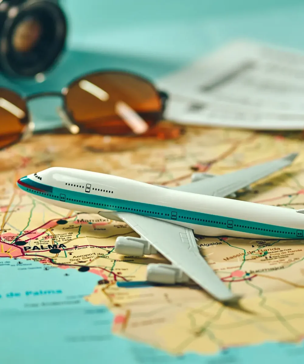 Embark on an adventure. Map, plane, camera, glasses and passport on the table. Travel, vacation concept.